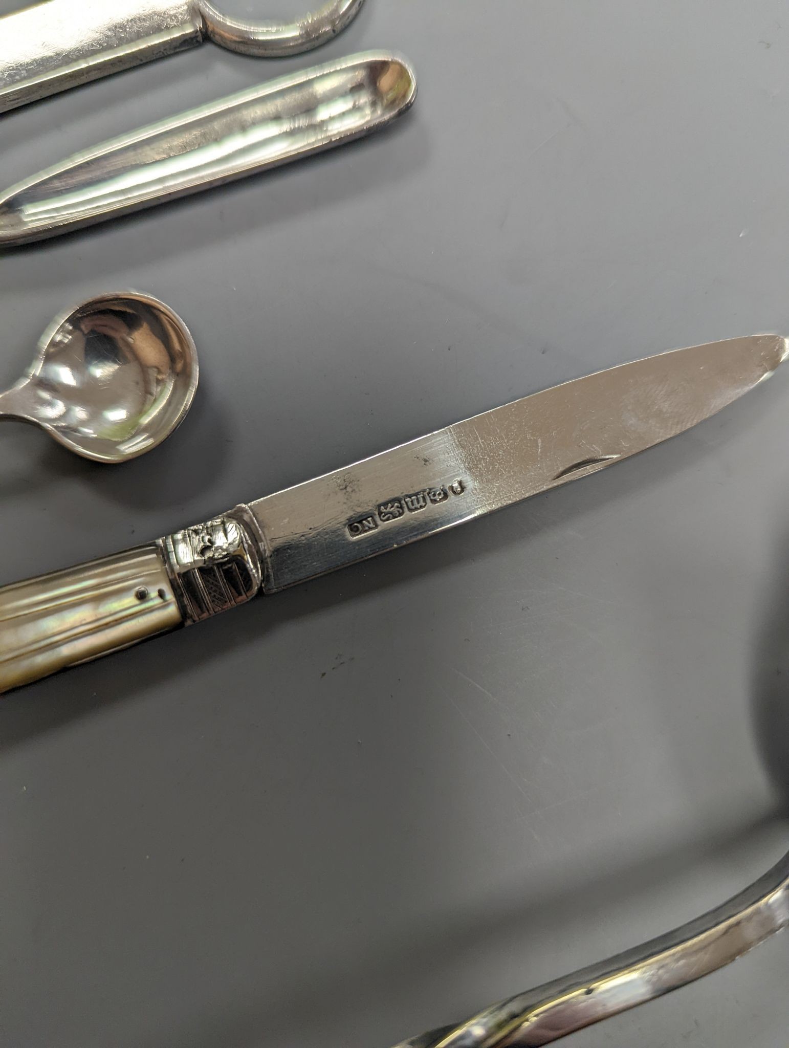 A George VI silver paper knife, London, 1937, a plated toddy ladle, two pairs of silver sugar tongs, damaged silver fruit knife and two other items.